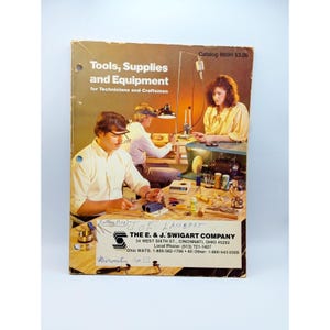 May include: A catalog cover for tools, supplies, and equipment for technicians and craftsmen. The cover features a photo of three people working on a workbench with various tools and equipment. The catalog is published by The E. & J. Swigart Company, located in Cincinnati, Ohio.
