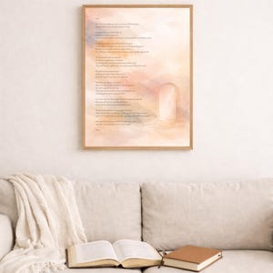 Op de afbeelding: Een ingelijste print met een aquarelachtergrond in tinten perzik, roze en blauw. De print bevat een gedicht met een lichtbruine houten lijst. Een open boek en een gesloten boek liggen op een beige bank, met een crèmekleurige deken.
