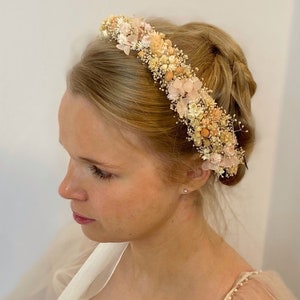 Pode incluir: Uma coroa floral delicada feita de flores secas em tons de creme, p&ecirc;ssego e rosa. A coroa &eacute; perfeita para um casamento ou ocasi&atilde;o especial.