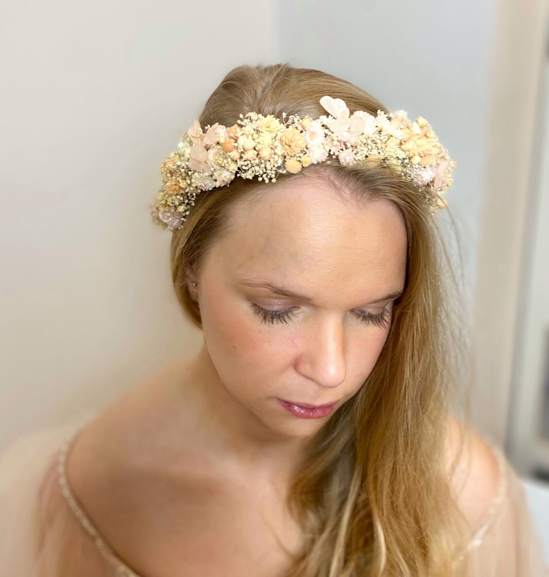 Pode incluir: Uma coroa floral delicada feita de flores secas em tons de p&ecirc;ssego e creme. A coroa &eacute; feita com flores pequenas e delicadas e &eacute; perfeita para um casamento ou ocasi&atilde;o especial.