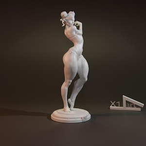 May include: White painted figurine of a woman in a swimsuit pose. The figurine is standing on a round base with a signature on the bottom.