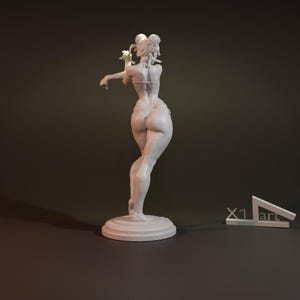 May include: White painted figurine of a woman in a bikini pose, standing on a round base. The figurine is sculpted in a realistic style and has a detailed finish.