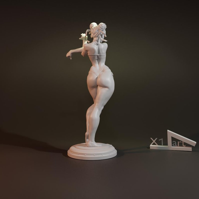 May include: White painted figurine of a woman in a bikini pose, standing on a round base. The figurine is sculpted in a realistic style and has a detailed finish.