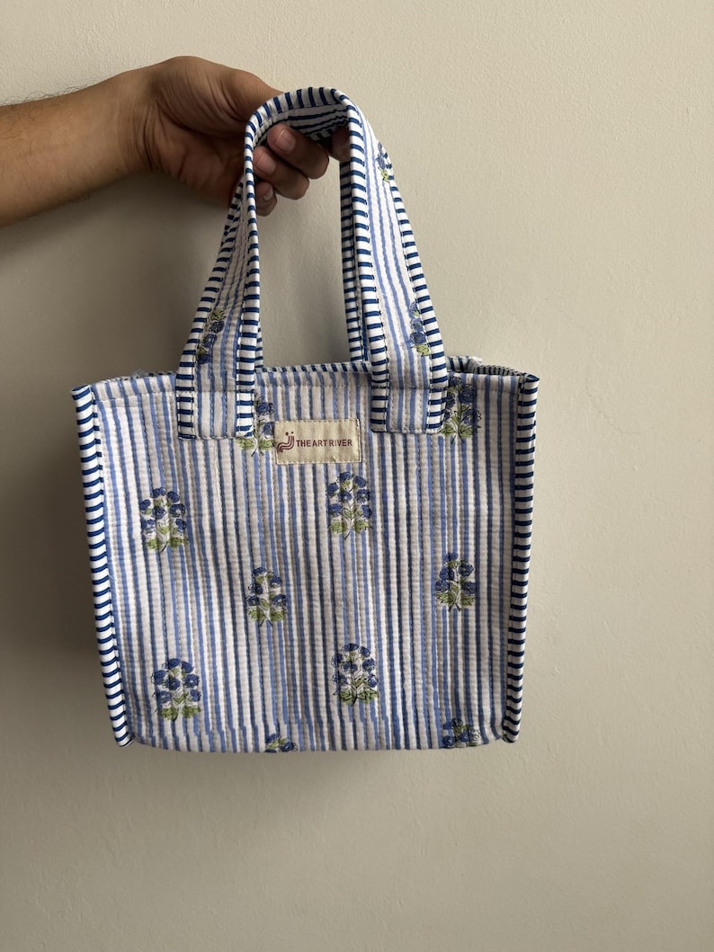 Handmade quilted cotton mini tote bag featuring blue vertical stripes with floral motifs, matching striped handles, and padded cotton construction.