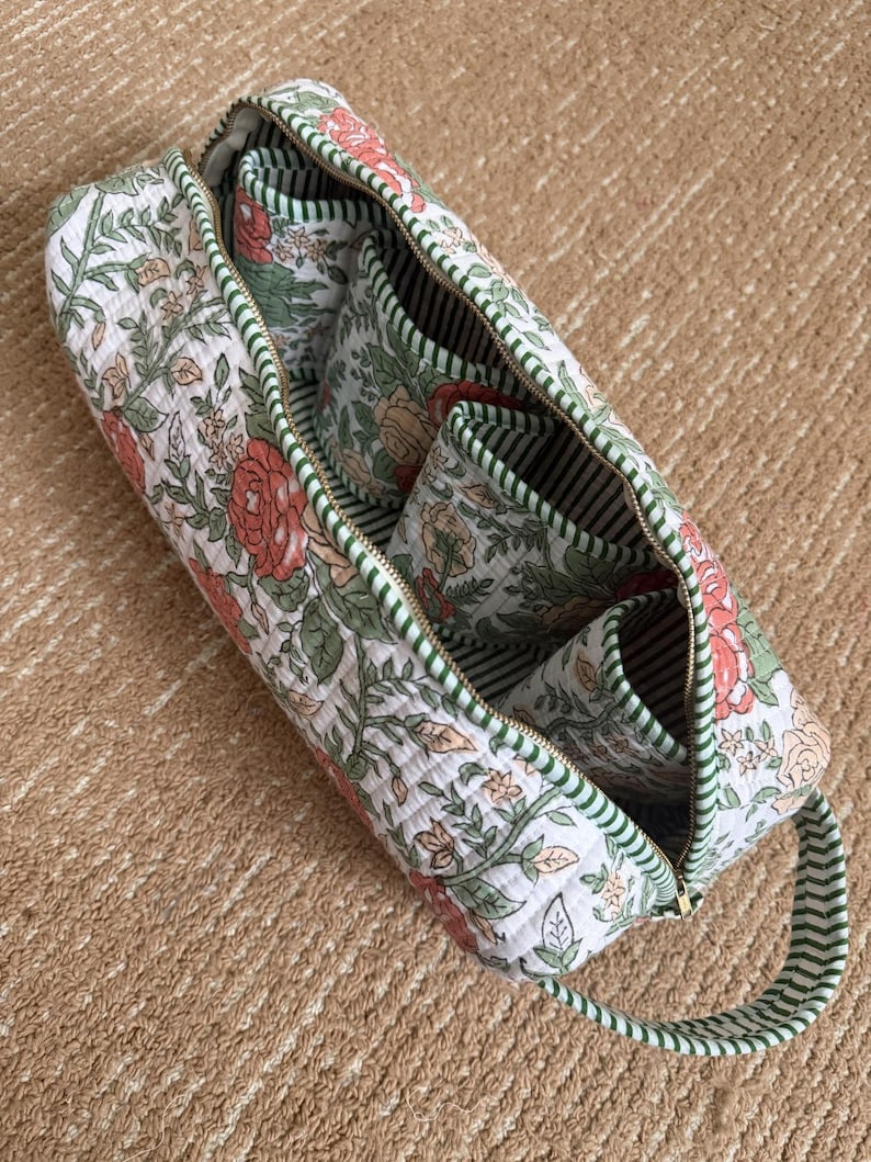 Floral hand block printed Dyson organizer bag opened to reveal four padded interior pockets, striped cotton lining, and spacious storage for Dyson Airwrap attachments.