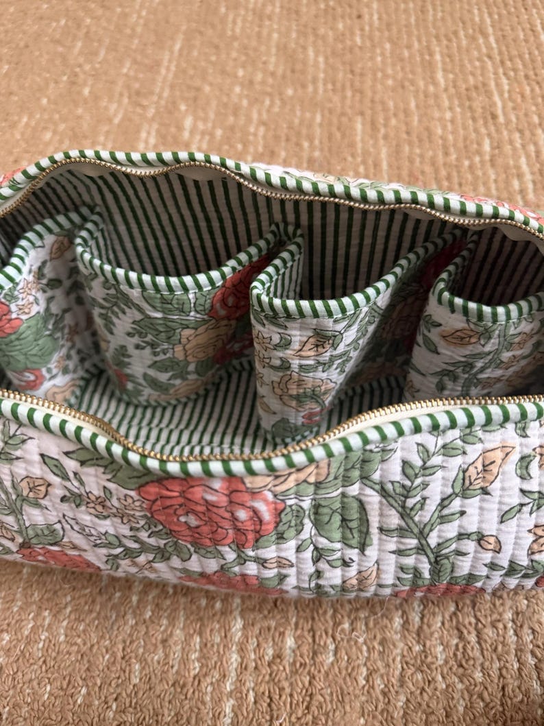 Hand block printed quilted Dyson Airwrap organizer with four padded interior pockets, green striped lining, and premium YKK zipper for secure storage.
