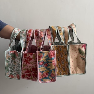 Collection of handmade quilted cotton mini tote bags featuring floral, polka dot, striped, and botanical prints in pink, blue, green, and cream color combinations.
