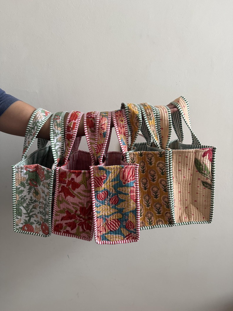Collection of handmade quilted cotton mini tote bags featuring floral, polka dot, striped, and botanical prints in pink, blue, green, and cream color combinations.