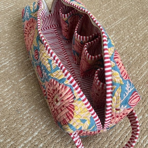 Blue floral hand block printed Dyson Airwrap organizer bag opened to show four padded accessory pockets, striped lining, and premium quilted cotton construction.