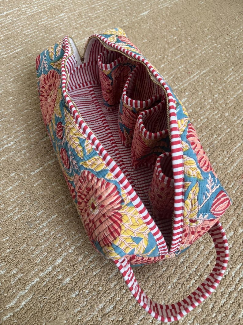 Blue floral hand block printed Dyson Airwrap organizer bag opened to show four padded accessory pockets, striped lining, and premium quilted cotton construction.