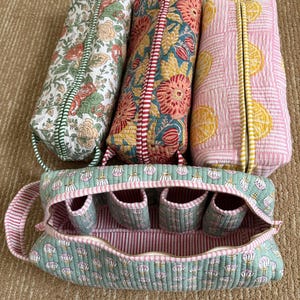 Hand block printed quilted Dyson Airwrap travel organizer displayed with three matching cotton accessory pouches, featuring four padded interior compartments and a premium YKK zipper.