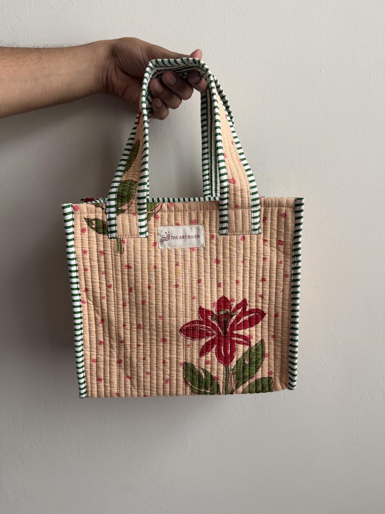 Handmade quilted cotton mini tote bag in soft beige with red lily flower print and green striped handles, ideal as a lunch bag or everyday carry tote.