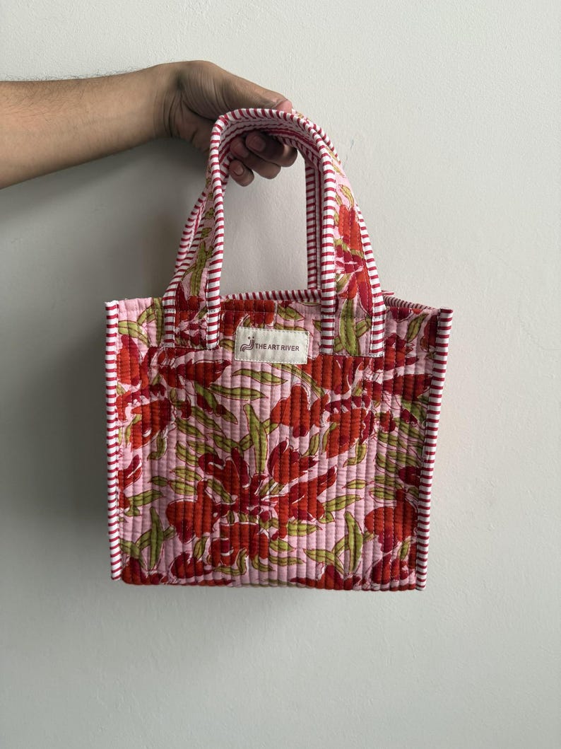 Handmade quilted cotton mini tote bag with pink floral block print, striped pink handles, and lightweight padded design for daily essentials.