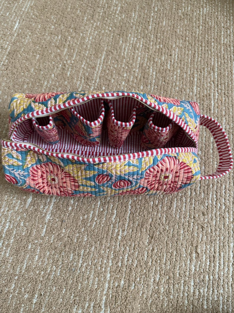 Quilted cotton blue floral hair tool organizer with red striped trim and carry handle.
