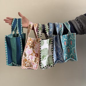 Könnte beinhalten: Ein Set aus drei Keramikbechern mit gesprenkelter, matter Oberfläche. Die Becher sind in Creme-, Hellbraun- und Dunkelbrauntönen gehalten. Jeder Becher hat ein schlichtes, minimalistisches Design.