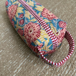 Handmade floral hair styling case with padded compartments and zipper closure.