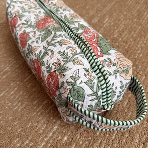 Quilted cotton floral hair tool organizer with green striped trim and carry handle.