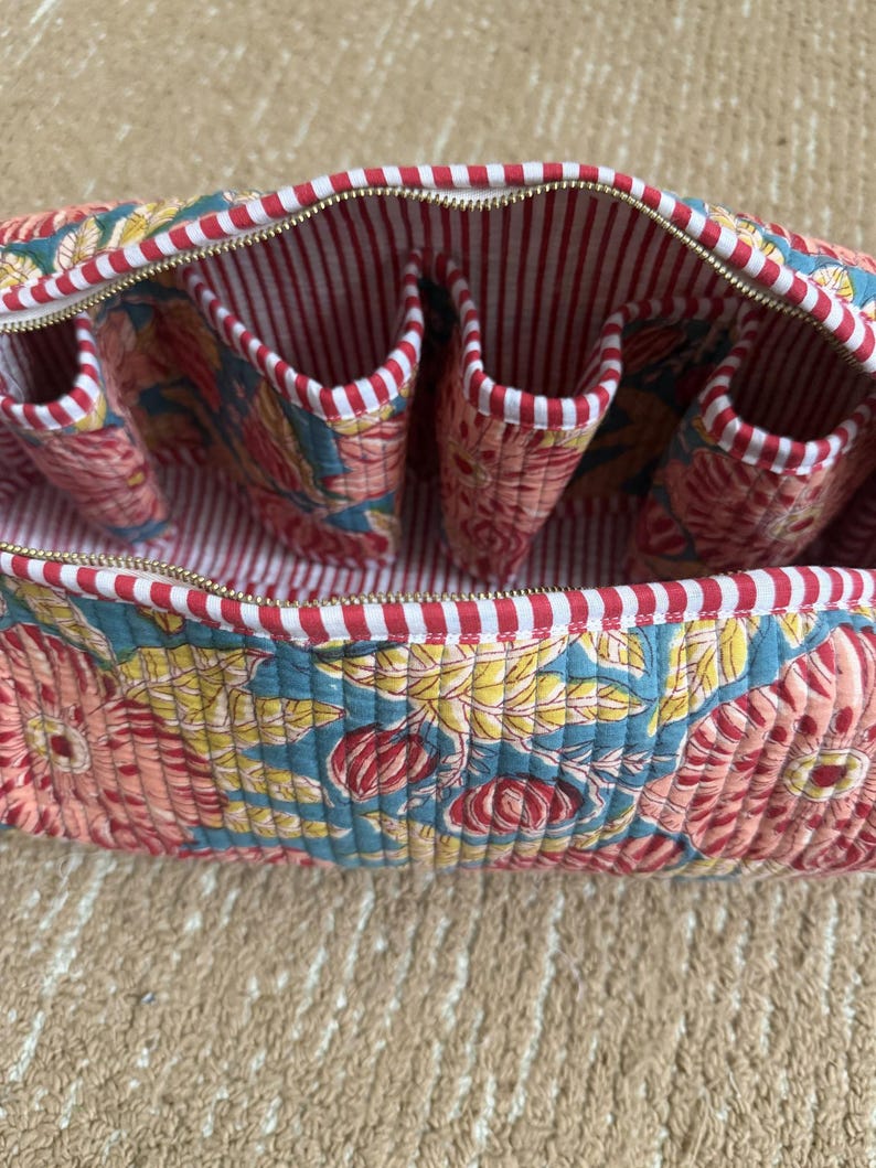 Open floral quilted Dyson storage case with four interior pockets, red striped cotton lining, premium YKK zipper, and organized compartments for Dyson attachments.
