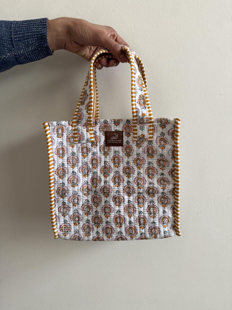 White and mustard hand block printed quilted mini lunch tote bag with striped piping and cotton handles.