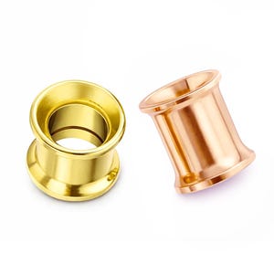 Könnte beinhalten: Zwei Ohr-Dehnungs-Schmuckstücke aus Metall. Eines ist goldfarben, das andere roségoldfarben. Beide haben ein ausgestelltes Design mit zylindrischem Körper und breitem, flachem Rand. Die Dehnungs-Schmuckstücke sind für gedehnte Ohrlöcher konzipiert.