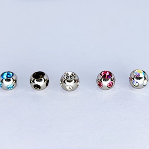 May include: Five silver ball beads with different colored rhinestones. The beads are round and have a smooth surface. The rhinestones are set in the beads and are visible from all sides.
