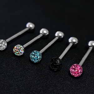 Puede incluir: Seis anillos de lengua de barra de plata con bolas de cristal de diferentes colores. Las bolas son transparentes, iridiscentes, azules, negras y rosas.
