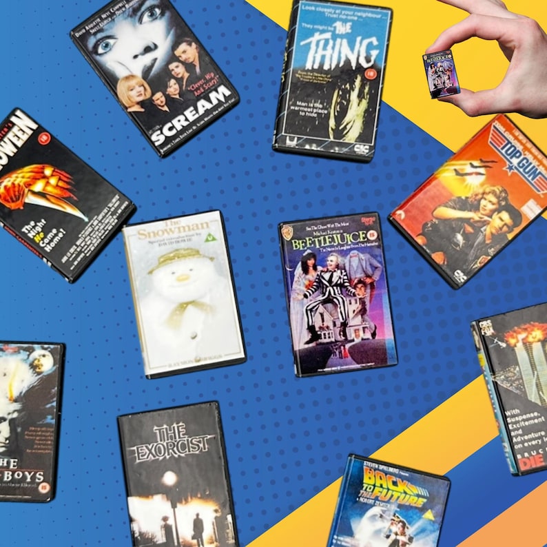 Puede incluir: Una colecci&oacute;n de estuches de pel&iacute;culas en miniatura, incluyendo "Scream", "The Thing" y "Beetlejuice", dispuestos sobre un fondo azul y amarillo. Los estuches presentan t&iacute;tulos y arte de pel&iacute;culas, mostrando una variedad de g&eacute;neros.