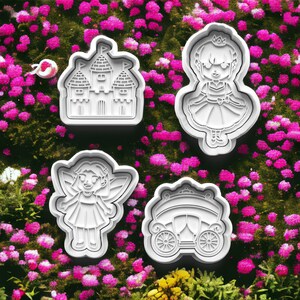 May include: Four white plastic cookie cutters shaped like a castle, a fairy, a princess, and a carriage. The cutters are on a background of pink flowers.