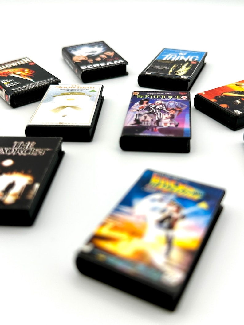 Puede incluir: Una colecci&oacute;n de mini estuches de DVD con t&iacute;tulos de pel&iacute;culas cl&aacute;sicas de terror y ciencia ficci&oacute;n. Los estuches tienen lomos negros y coloridas portadas, incluyendo "Halloween", "Scream" y "The Thing". Los DVD est&aacute;n dispuestos sobre una superficie blanca.