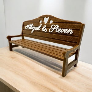 May include: A brown wooden bench with a heart-shaped back and the names "Abigail & Steven" written in white on the front.