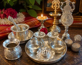 May include: A collection of silver-toned metal ritual items including a small bowl with a spoon, a lidded container with floral engravings, a central tray holding two small bowls and a flower-shaped incense holder, and a tall decorative stand.