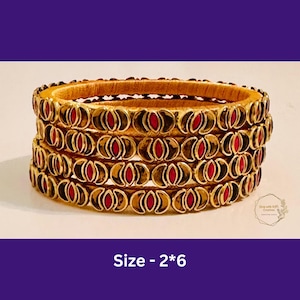 May include: Six gold bangles with red enamel accents. The bangles are stacked on top of each other. The text "Size - 2*6" is visible below the bangles.
