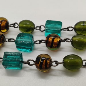 May include: A multi-colored glass bead necklace with a silver chain. The beads are green, blue, and brown.