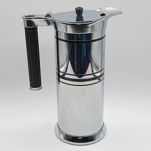 May include: A silver pitcher with a black handle and a lid. The pitcher has two black bands around the body.