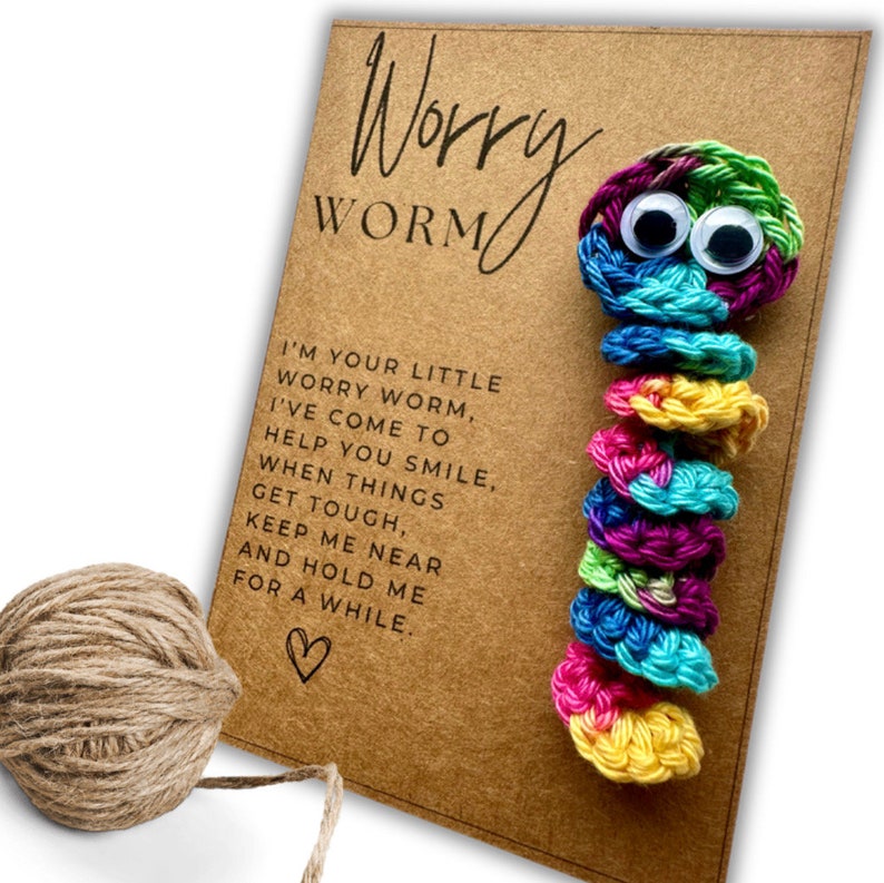 Puede incluir: Un gusano de la preocupaci&oacute;n de crochet colorido con ojos saltones en una tarjeta marr&oacute;n con el texto "Worry Worm" y el mensaje "Soy tu peque&ntilde;o gusano de la preocupaci&oacute;n, he venido para ayudarte a sonre&iacute;r, cuando las cosas se pongan dif&iacute;ciles, mantenme cerca y abr&aacute;zame un rato."
