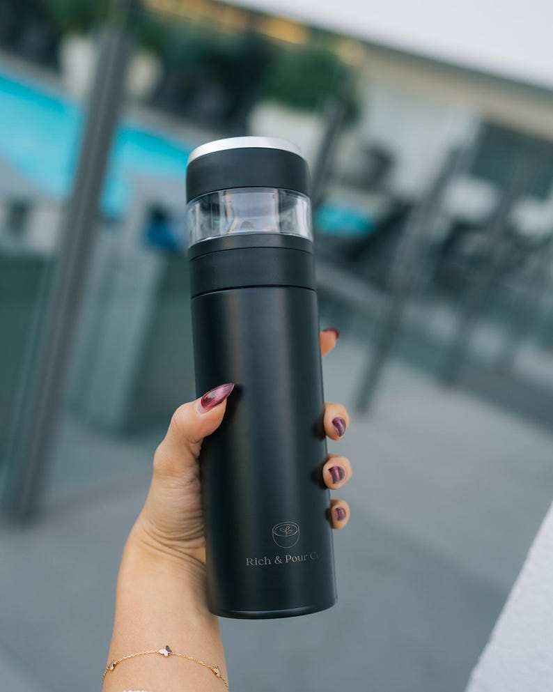 May include: A black stainless steel water bottle with a silver lid and a logo that says "Rich & Pour Co."
