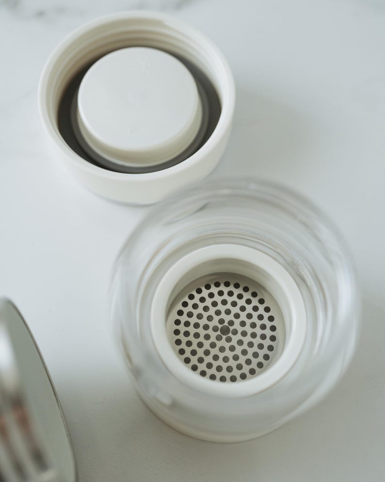 May include: A white lid with a smaller white lid inside, and a clear glass lid with a metal mesh filter inside.
