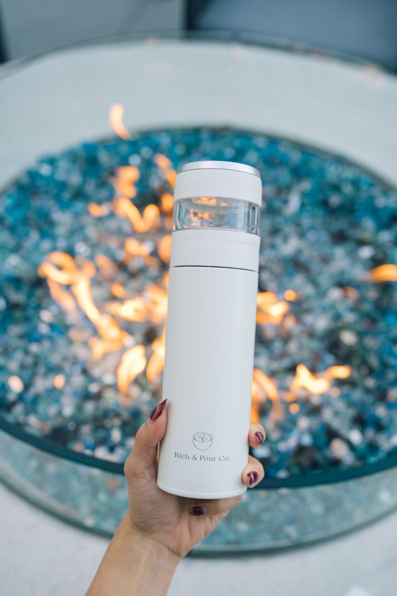 May include: White stainless steel travel mug with a clear lid and a logo that says "Rich & Pour Co."