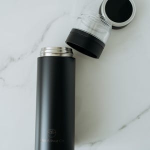 May include: A black stainless steel travel mug with a silver lid and a logo that says "Stitch & Pour Co."