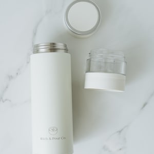 May include: White stainless steel thermal bottle with a white lid and a white and clear glass infuser. The bottle has the text "Rich & Pour Co." printed on the side.