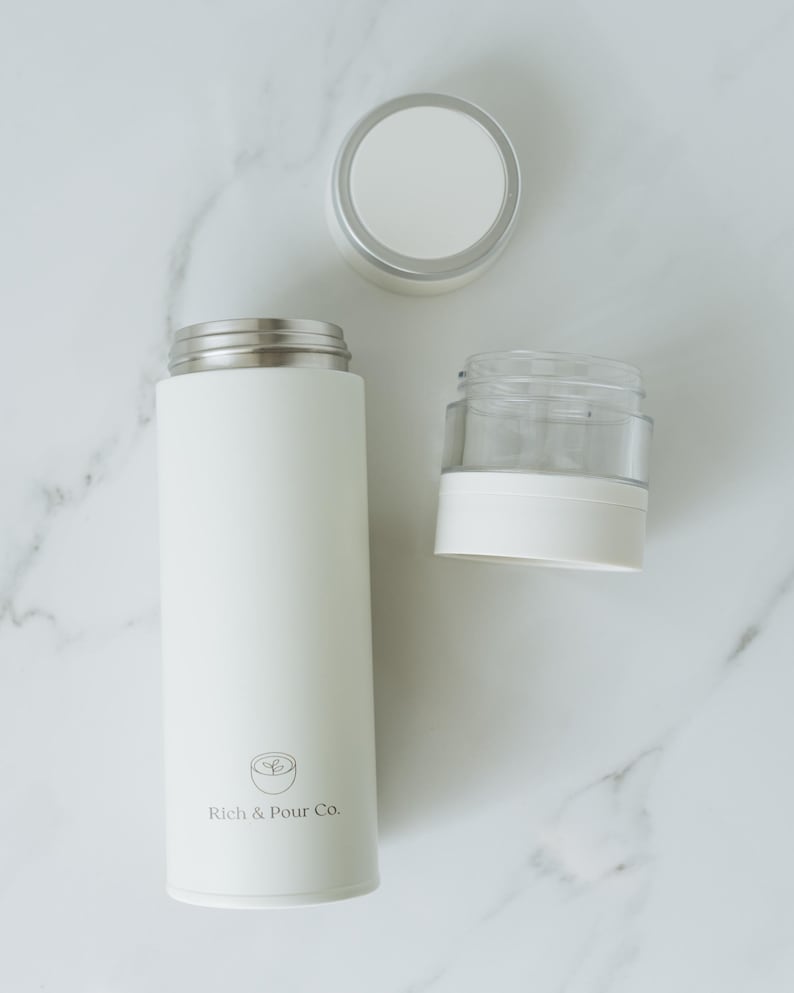 May include: White stainless steel thermal bottle with a white lid and a white and clear glass infuser. The bottle has the text "Rich & Pour Co." printed on the side.