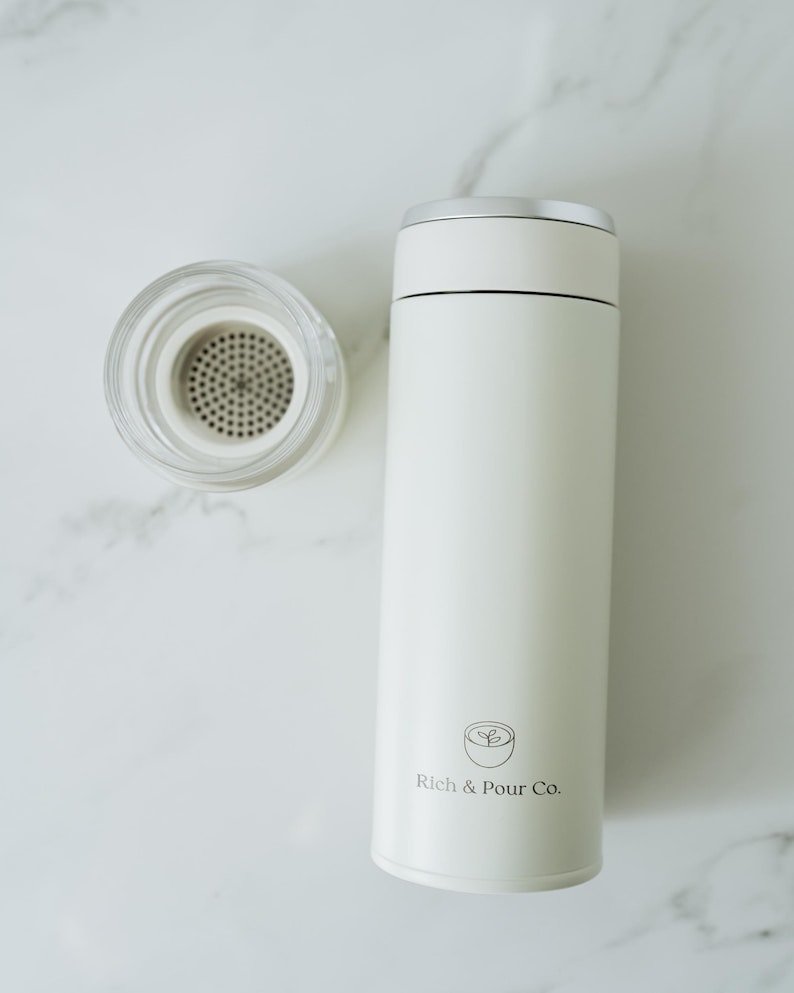 May include: White stainless steel travel mug with a lid and a logo that says "Rich & Pour Co."