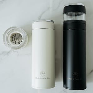 May include: Two stainless steel thermal coffee tumblers with a built-in infuser. The tumbler on the left is white with the text "Rich & Pour Co." The tumbler on the right is black with the text "Rich & Pour Co."