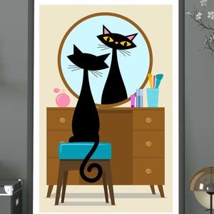 May include: A framed print featuring a mid-century modern illustration of a black cat sitting on a blue stool in front of a vanity mirror. The mirror reflects the cat's image. A perfume bottle and makeup brushes are on the vanity.