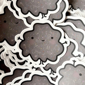 May include: A stack of black and white stickers featuring a cartoon cloud with a smiling face and confetti inside. The cloud has two arms and two legs.