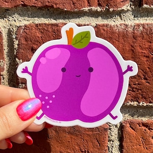May include: A purple cartoon plum with a happy face and a green leaf on top. The plum has a white outline and is on a white background. The text "@PLUMPPRESS.CO" is at the bottom of the sticker.