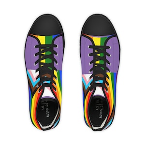 Może przedstawiać: Para czarnych, wysokich butów z płótna z wzorem tęczowej flagi dumy. Buty mają czarne sznurówki i białą podeszwę. Tekst "US | EU M/10F/12" jest nadrukowany wewnątrz każdego buta.