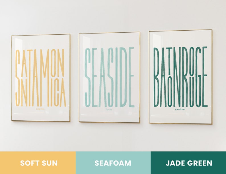 Puede incluir: Tres impresiones enmarcadas con marcos dorados y fondos blancos. Las impresiones presentan las palabras "Catamon Jamaica", "Seaside" y "Bathhouse Bondi" en diferentes colores. Los colores son sol suave, espuma de mar y verde jade.