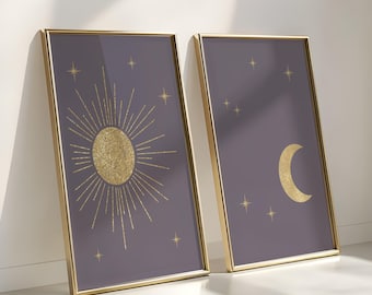 May include: Two framed celestial art prints. One features a gold sunburst design, the other a gold crescent moon, both set against a dark purple background. Gold stars are scattered across the backgrounds. The frames are gold.