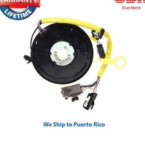 May include: A black steering wheel column with a yellow wire and a black and white connector. The steering wheel column is a replacement part for a car.